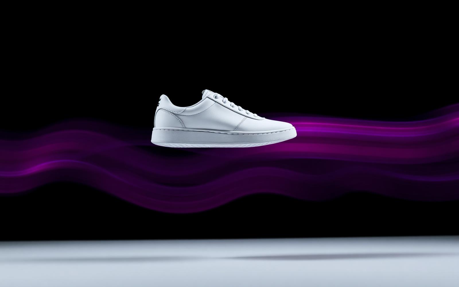 A white sneaker mid-air with magenta motion trails